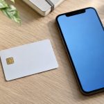 Card alb cu cip electronic și telefon mobil pe un birou de lemn