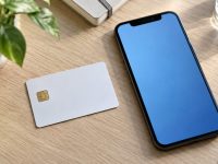 Card alb cu cip electronic și telefon mobil pe un birou de lemn